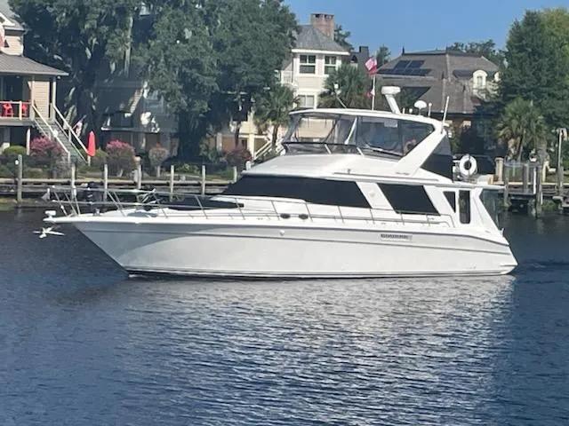 Dragonfly Yacht Photos Pics 1997 Sea Ray 550 Sedan Bridge yacht cruising on a calm river near waterfront homes.