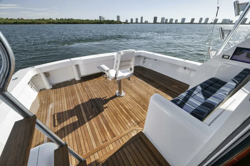 Big Fish II Yacht Photos Pics 2005 Viking Convertible boat deck with wooden flooring, overlooking calm waters and distant city skyline.
