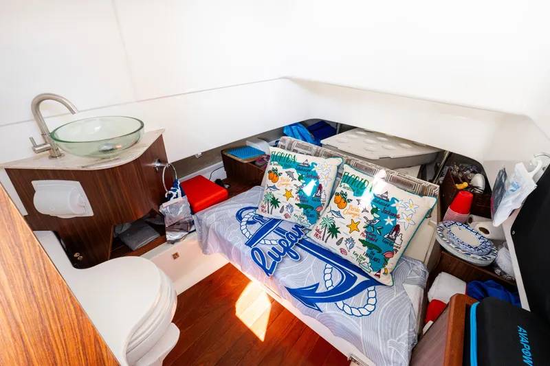  Yacht Photos Pics 2023 Pursuit S 328 Sport cabin with cozy bedding, pillows, and compact sink area.