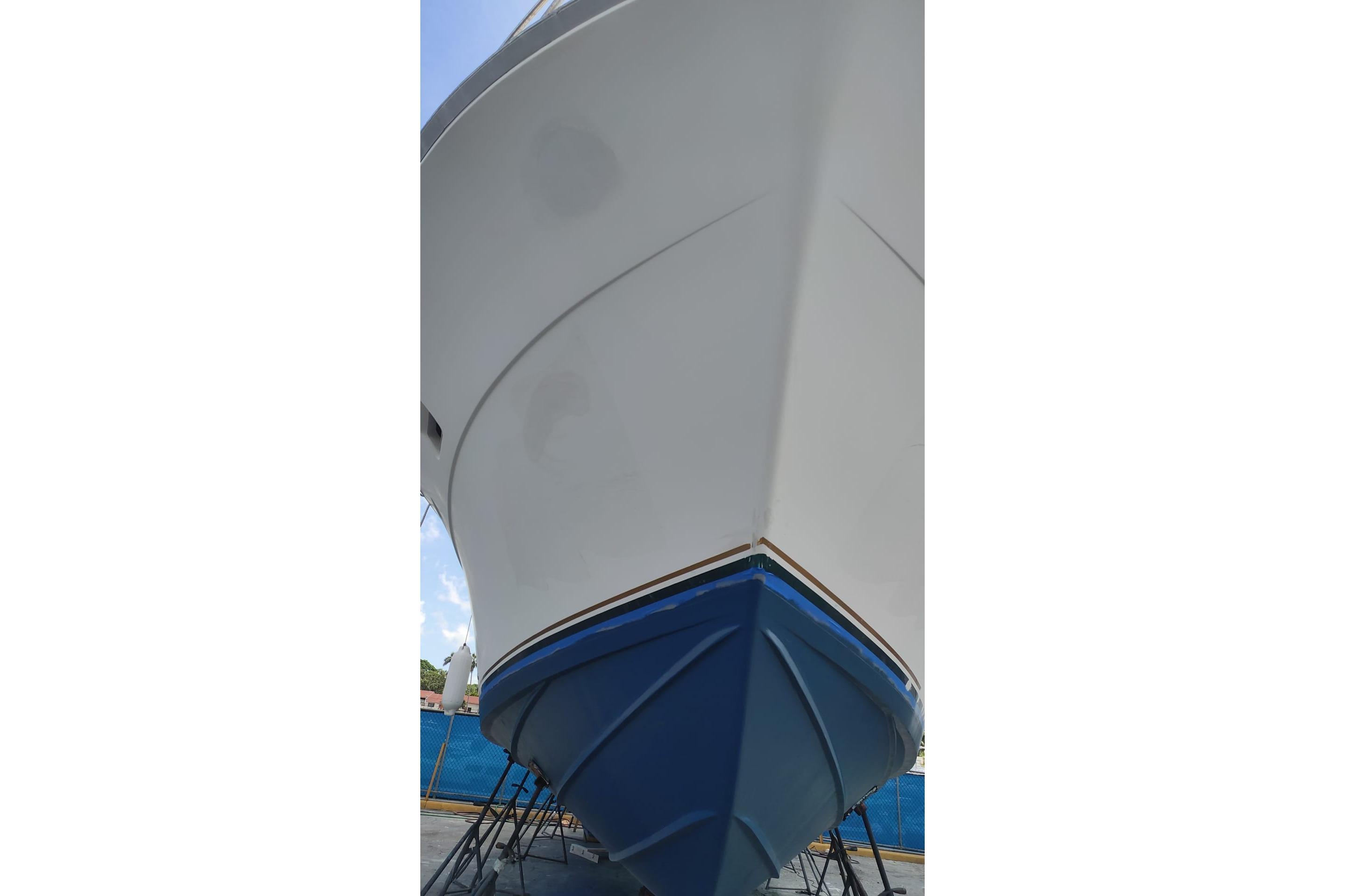 1977 Bertram 46 Convertible boat, white and blue hull, docked on stands.