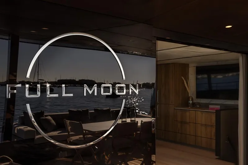 Full Moon Yacht Photos Pics Luxurious 2024 Moon 60 Sail yacht interior with "Full Moon" logo, overlooking serene waters.