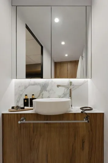 Full Moon Yacht Photos Pics Modern bathroom vanity with marble backsplash and wooden cabinet, featuring a sleek vessel sink.