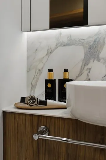 Full Moon Yacht Photos Pics Luxury bathroom with marble backsplash, wooden cabinet, and elegant toiletries on a tray. Moon 60 Sail 2024.