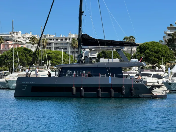 Full Moon Yacht Photos Pics 2024 Moon 60 Sail yacht docked in a marina, surrounded by other boats and lush greenery.