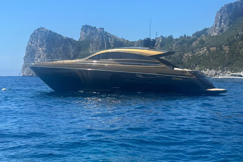 Candyman Yacht Photos Pics Luxury 2009 Pershing 64 yacht anchored in scenic coastal waters with rocky cliffs.