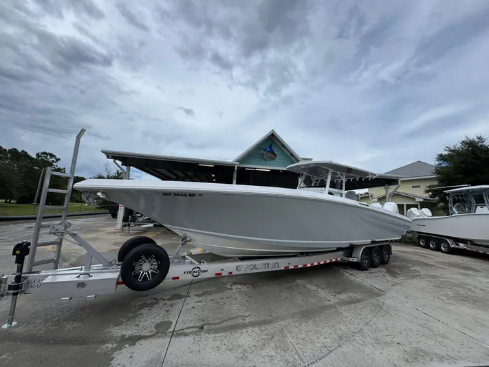  Yacht Photos Pics 2022 Fountain 38 CC boat on trailer, parked outdoors under cloudy sky.