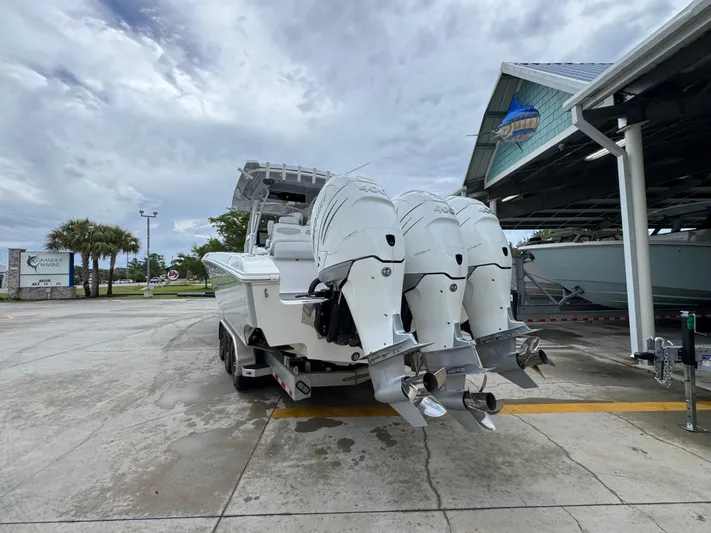  Yacht Photos Pics 2022 Fountain 38 CC boat with triple outboard engines in a marina setting.