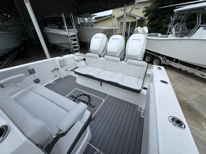  Yacht Photos Pics 2022 Fountain 38 CC boat interior with seating and outboard motors in a marina setting.