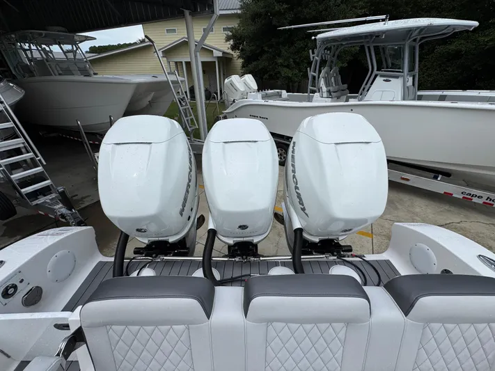  Yacht Photos Pics 2022 Fountain 38 CC boat with triple Mercury outboard engines in a covered storage area.