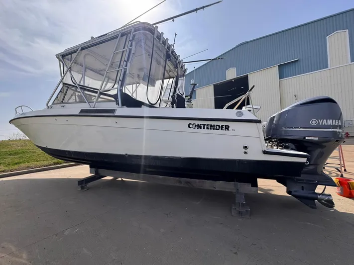  Yacht Photos Pics 1998 Contender 35 Express Side Console boat with Yamaha outboard, docked near a blue building.