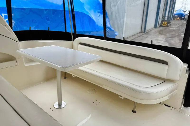  Yacht Photos Pics 2004 Searay 360 Sundancer interior with white seating and table, docked near blue tarps.