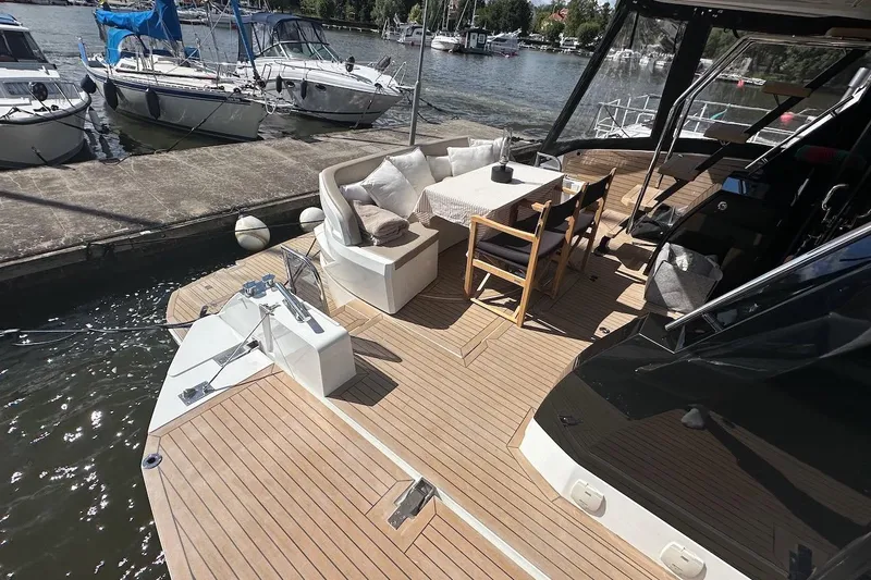  Yacht Photos Pics 2024 Galeon 500 Fly yacht deck with seating and dining area, docked at marina.