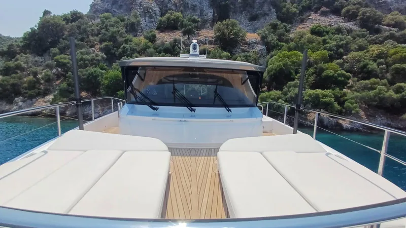  Yacht Photos Pics Luxurious 2024 Princess X80 yacht with sunbeds, cruising near scenic rocky coastline.