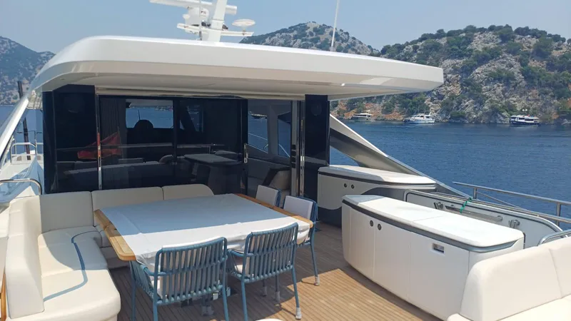  Yacht Photos Pics Luxurious 2024 Princess X80 yacht deck with dining area, overlooking serene waters and scenic hills.