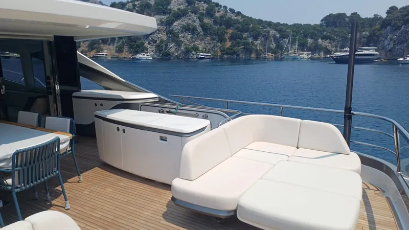  Yacht Photos Pics Luxurious 2024 Princess X80 yacht deck with seating, overlooking serene waters and lush coastline.