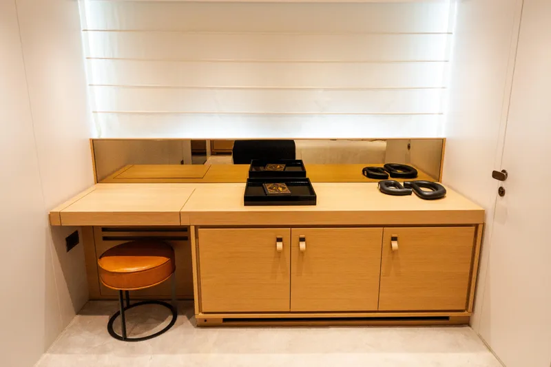 Gatsby Yacht Photos Pics Modern vanity area on 2021 Sanlorenzo SL96 yacht with wooden cabinetry and leather stool.