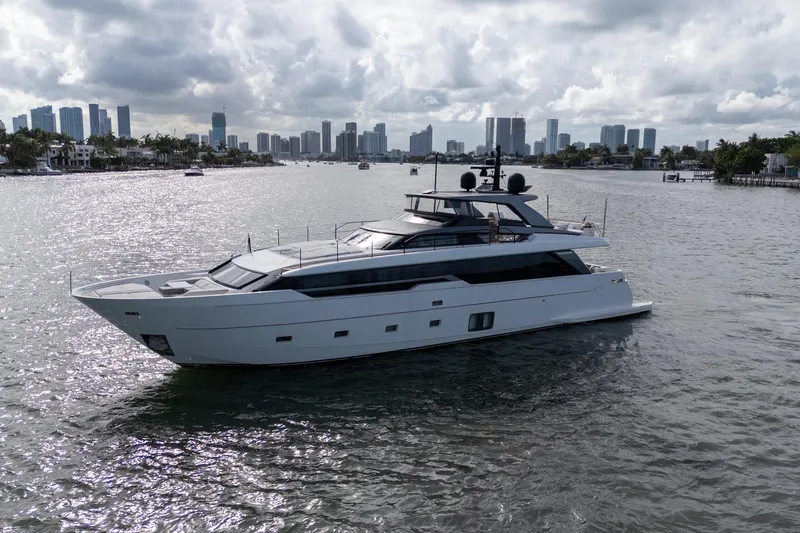 Gatsby Yacht Photos Pics 2021 Sanlorenzo SL96 yacht cruising near a city skyline under cloudy skies.