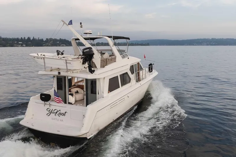 Y Knot Yacht Photos Pics 2003 Navigator 4800 yacht cruising on a serene lake near Seattle, displaying American flag.