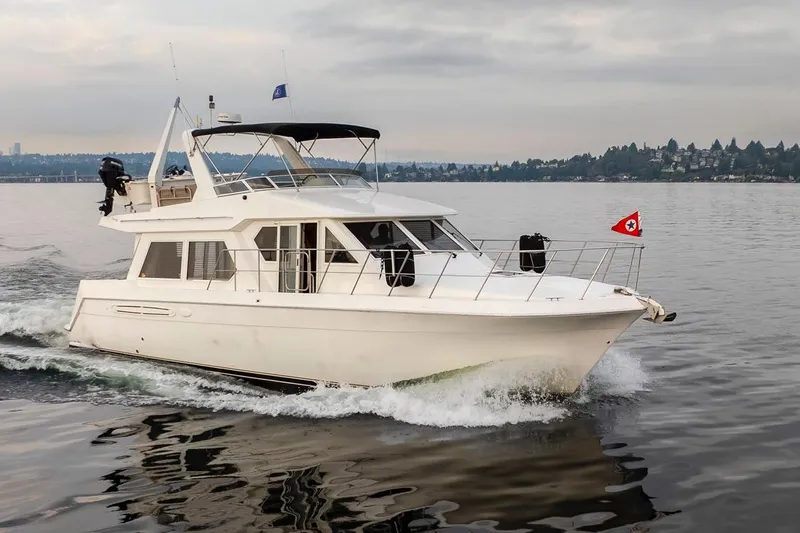 Y Knot Yacht Photos Pics 2003 Navigator 4800 yacht cruising on calm waters under a cloudy sky.