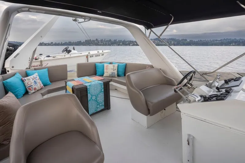 Y Knot Yacht Photos Pics Luxurious 2003 Navigator 4800 yacht interior with seating, cushions, and helm, overlooking serene waters.