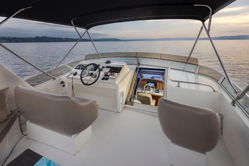 Y Knot Yacht Photos Pics 2003 Navigator 4800 yacht helm with dual seats, steering wheel, and serene water view.
