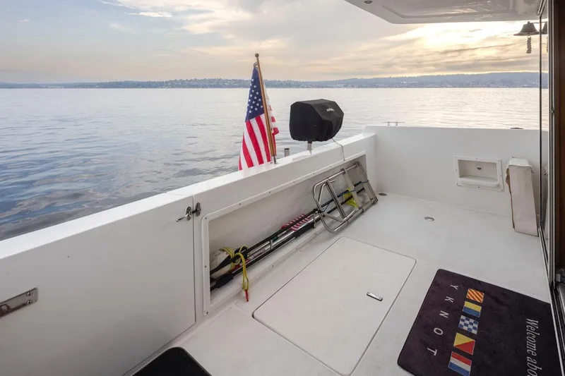 Y Knot Yacht Photos Pics 2003 Navigator 4800 yacht deck with American flag, overlooking serene water and distant shoreline.