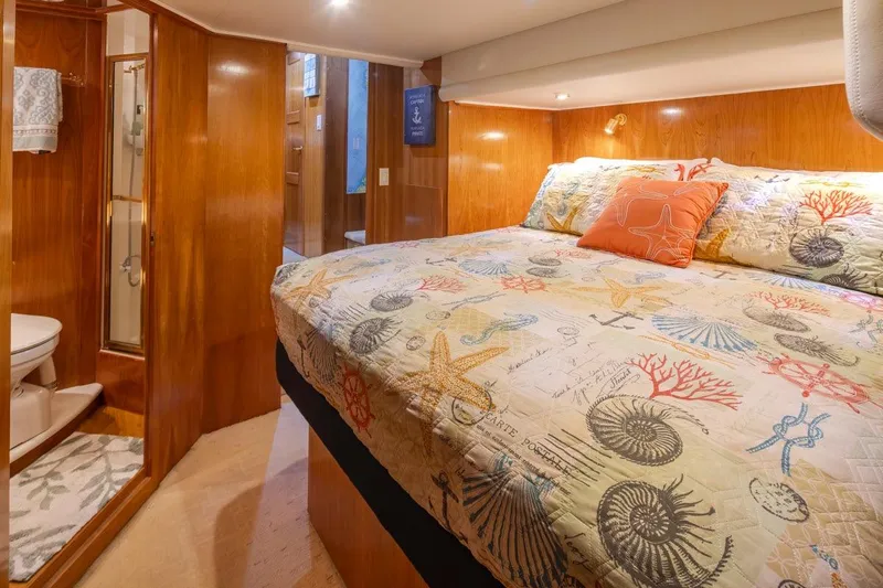 Y Knot Yacht Photos Pics Luxurious 2003 Navigator 4800 yacht bedroom with nautical-themed bedding and ensuite bathroom.