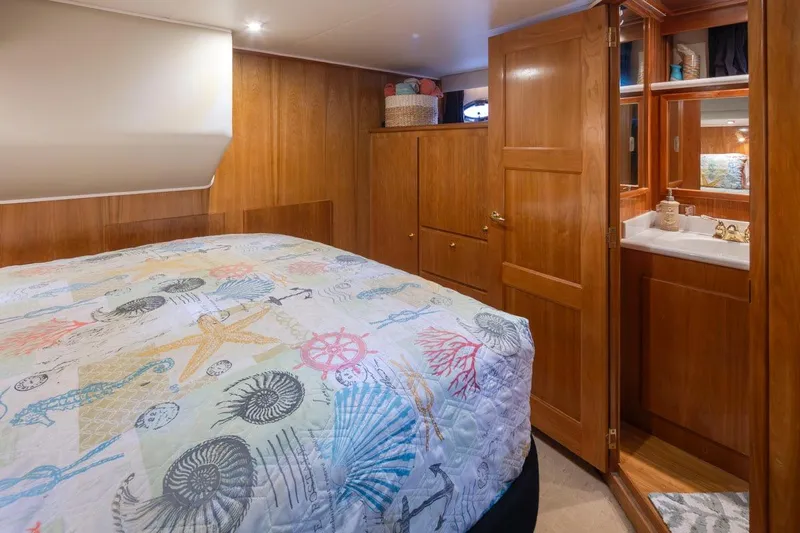 Y Knot Yacht Photos Pics Cozy bedroom in 2003 Navigator 4800 yacht with nautical-themed bedding and wooden cabinetry.