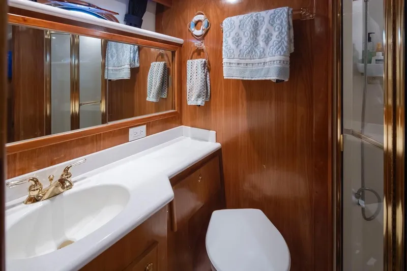 Y Knot Yacht Photos Pics Luxurious 2003 Navigator 4800 yacht bathroom with wood paneling and gold fixtures.