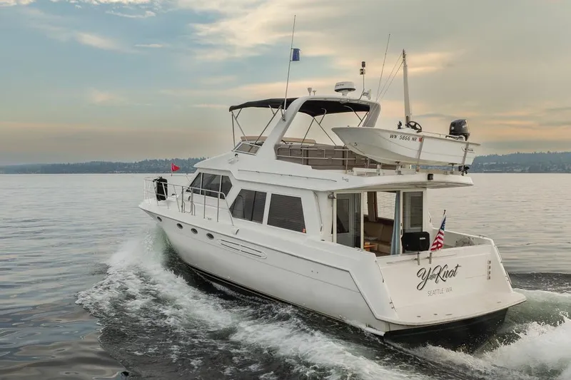 Y Knot Yacht Photos Pics 2003 Navigator 4800 yacht cruising on calm waters under a cloudy sky.