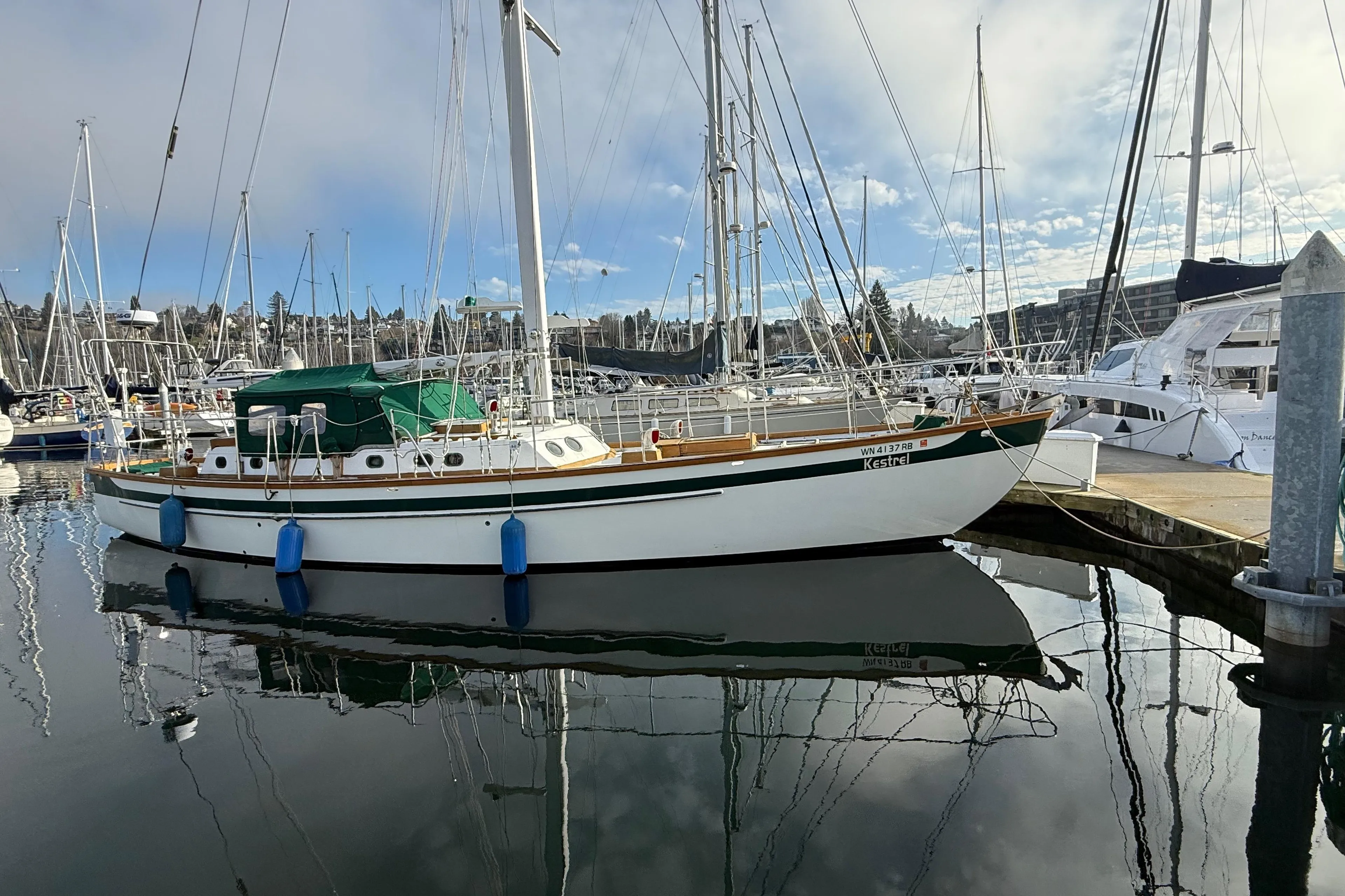 Sailboat docked at marina, HMMD 46 model, 1990, with clear reflections on water.