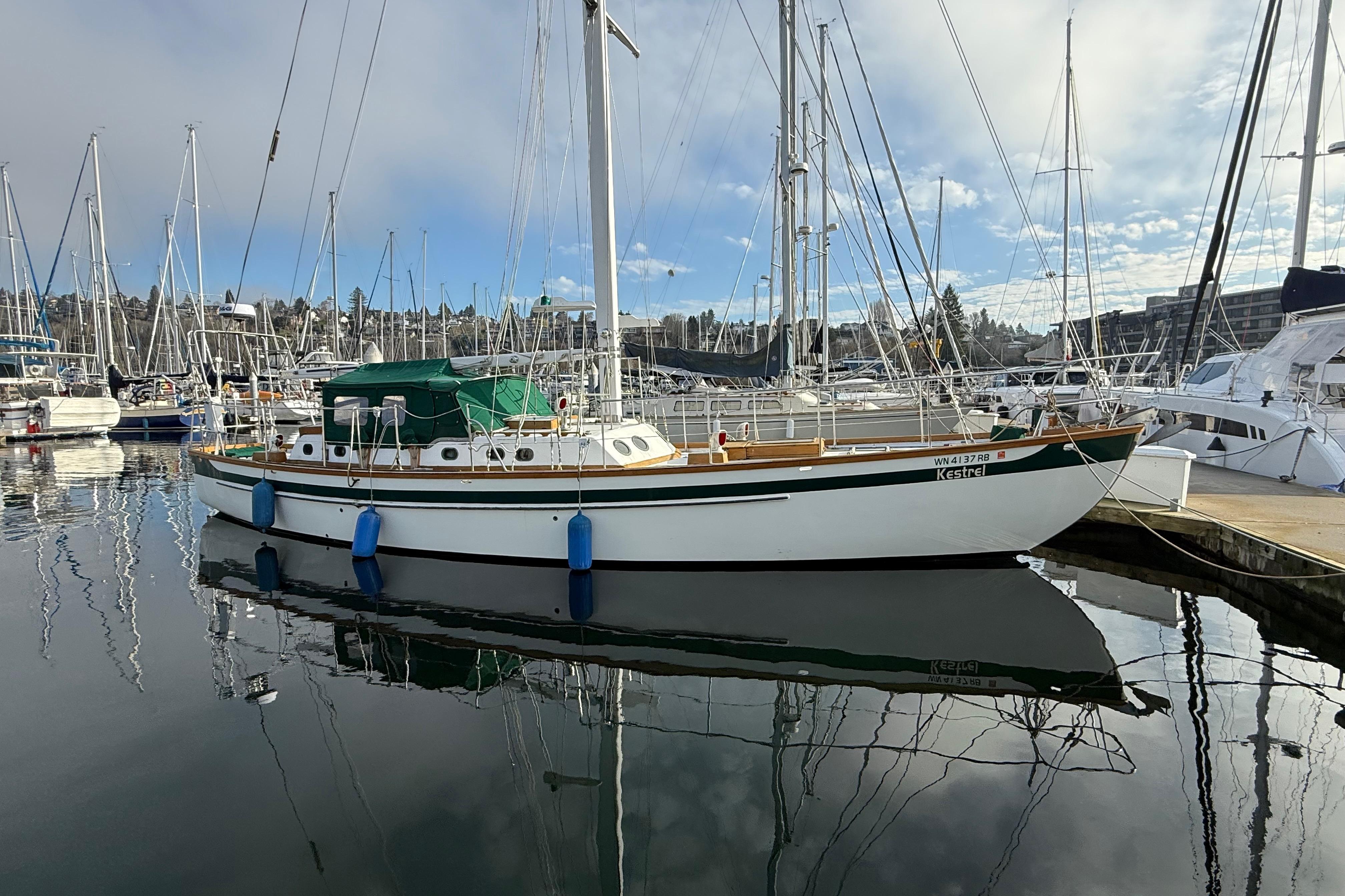 Sailboat docked in marina, HMMD 46 model, 1990, with clear sky reflection.