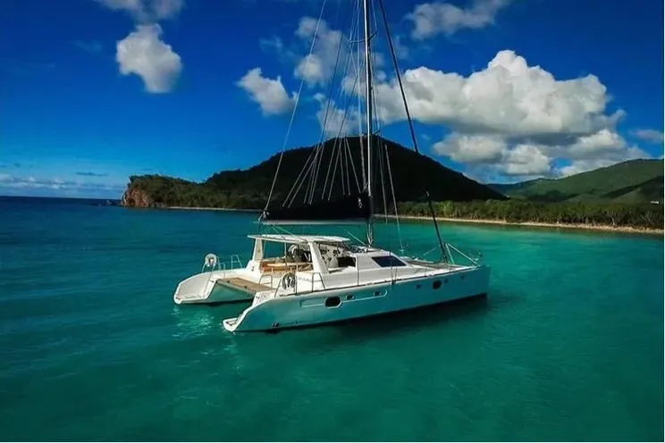 Electrify Yacht Photos Pics 2018 Voyage Yachts 480E catamaran sailing in clear turquoise waters near a lush coastline.