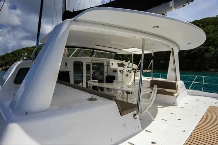 Electrify Yacht Photos Pics 2018 Voyage Yachts 480E catamaran with spacious deck and seating area, docked by lush greenery.
