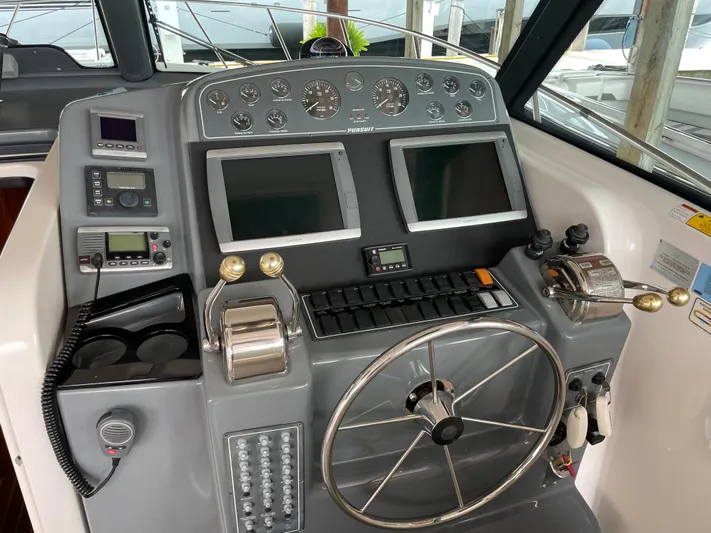  Yacht Photos Pics Control panel of a 2002 Pursuit 3800 Express boat with dual screens and steering wheel.