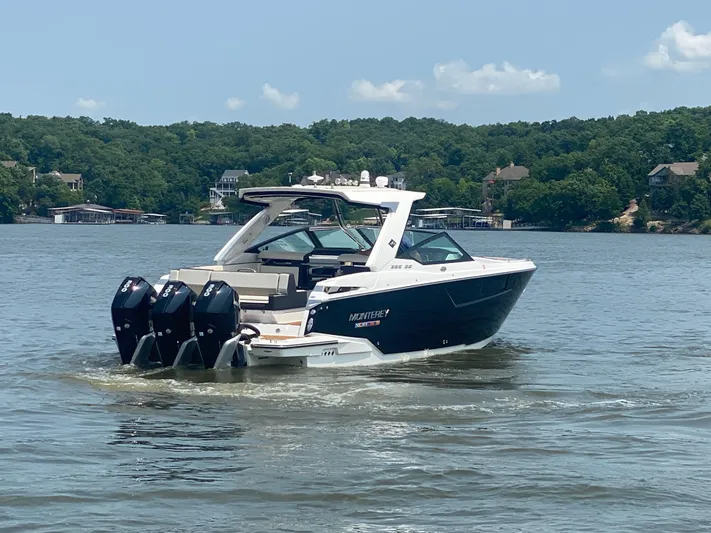  Yacht Photos Pics 2022 Monterey 385 Super Sport boat cruising on a lake with scenic forested shoreline.