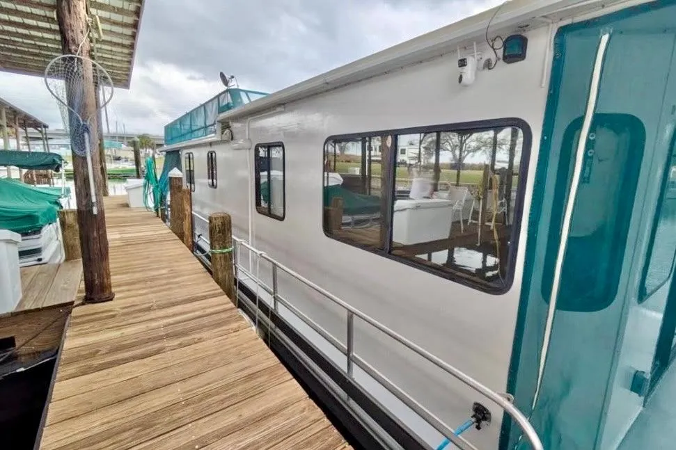 1986 Stardust Cruisers 52 houseboat docked, featuring wooden walkway and covered marina.