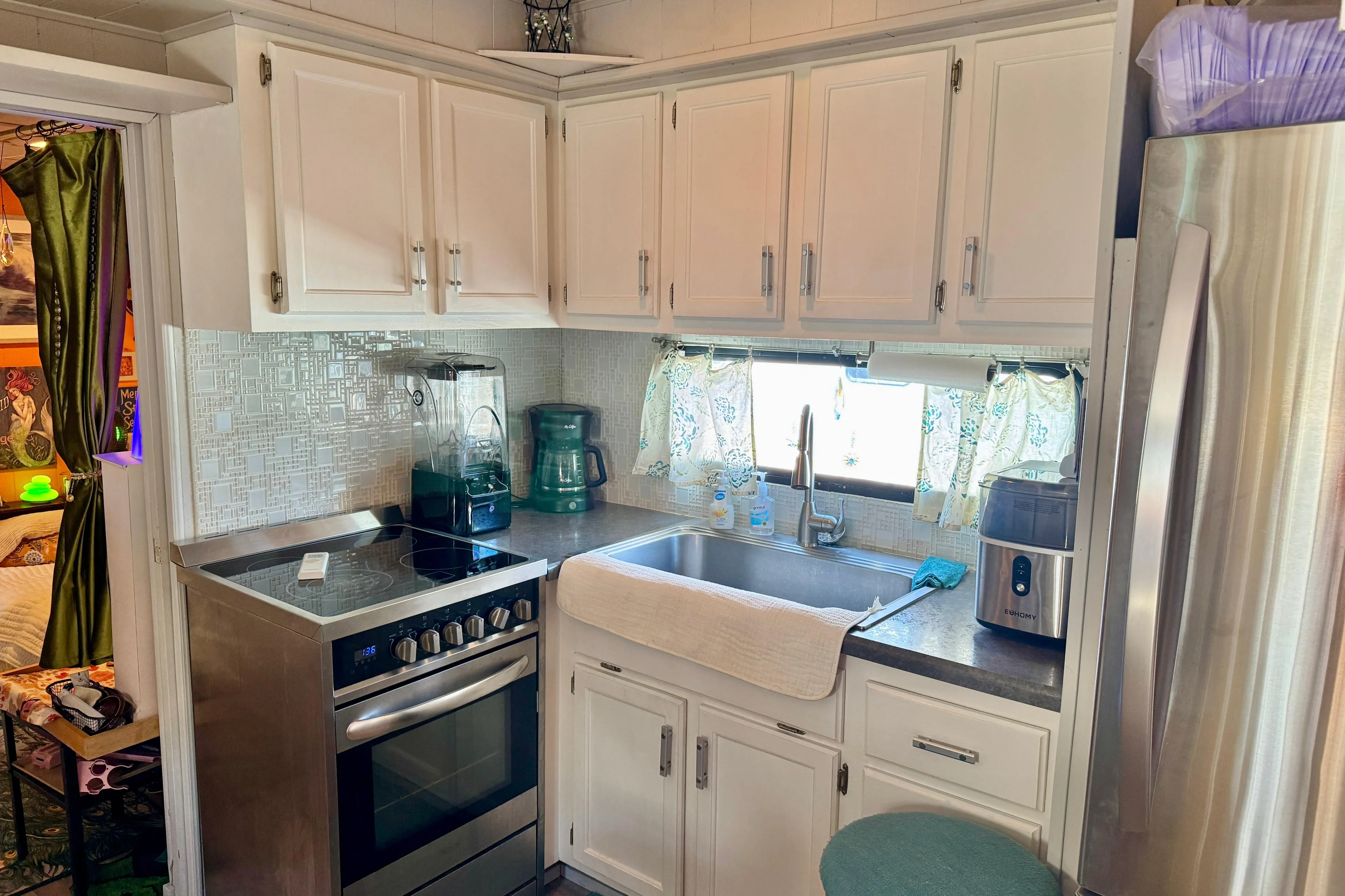 Compact kitchen in a 1986 Stardust Cruisers 52, featuring modern appliances and white cabinetry.