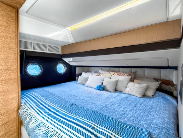  Yacht Photos Pics Luxurious bedroom interior of 2013 Azimut 64 yacht with blue bedding and porthole windows.