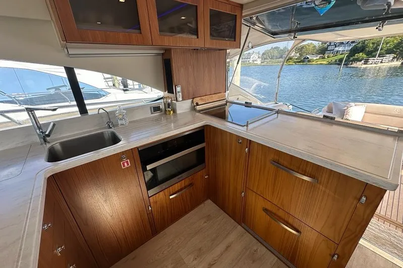 Happy Ours Yacht Photos Pics Luxurious 2019 Riviera 5400 Sport Yacht kitchen with wood cabinetry and waterfront view.