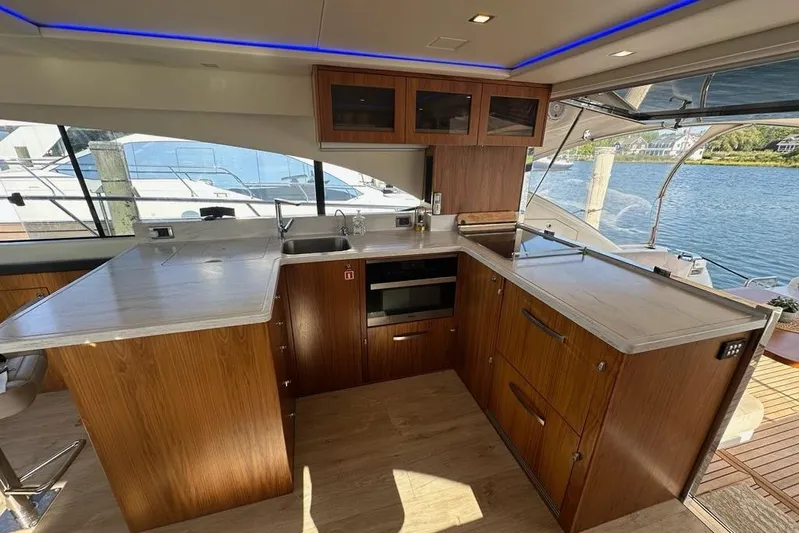 Happy Ours Yacht Photos Pics Luxurious 2019 Riviera 5400 Sport Yacht kitchen with modern wood cabinetry and waterfront view.