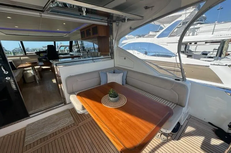 Happy Ours Yacht Photos Pics 2019 Riviera 5400 Sport Yacht interior with elegant seating and wooden table.