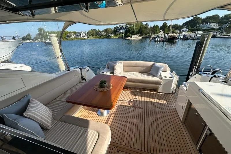 Happy Ours Yacht Photos Pics 2019 Riviera 5400 Sport Yacht interior with elegant seating and wooden table by the water.