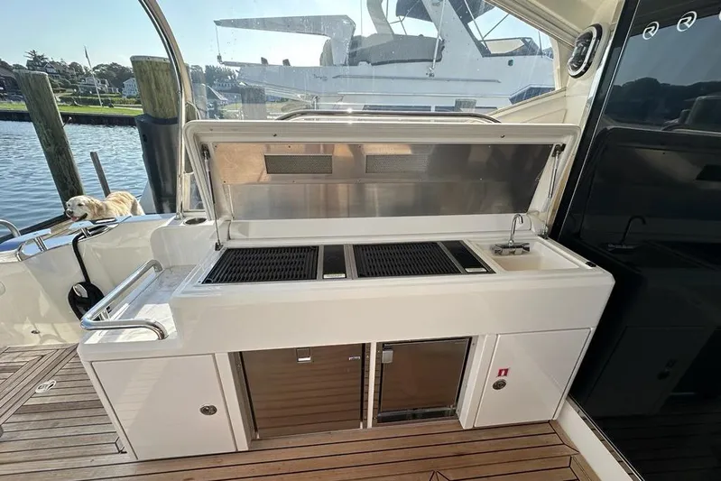 Happy Ours Yacht Photos Pics Outdoor kitchen on 2019 Riviera 5400 Sport Yacht with grill and sink, docked by water.