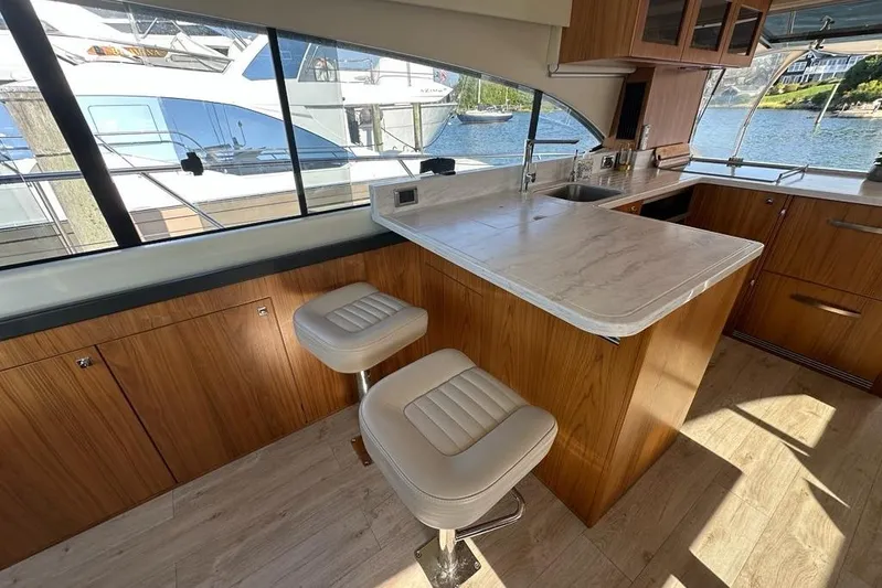 Happy Ours Yacht Photos Pics Luxurious interior of 2019 Riviera 5400 Sport Yacht with modern kitchen and seating.