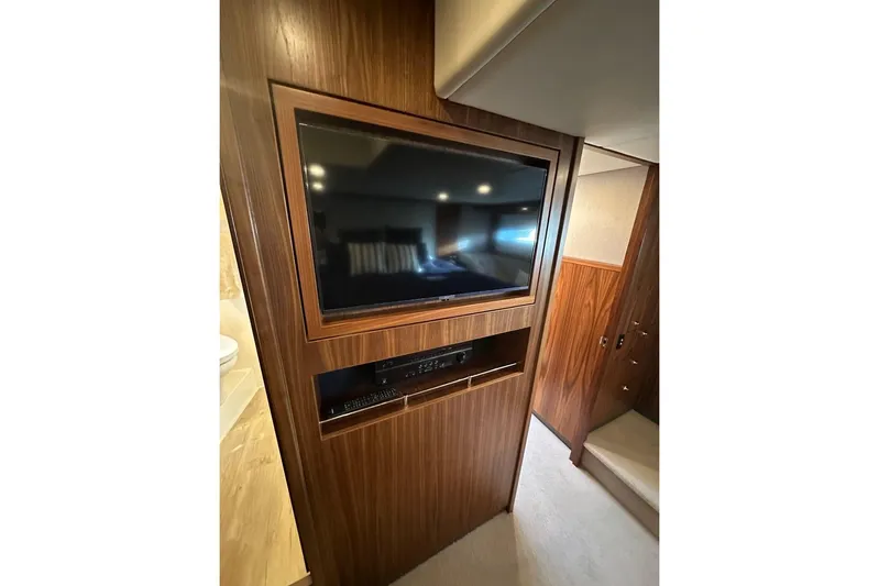 Happy Ours Yacht Photos Pics 2019 Riviera 5400 Sport Yacht interior with built-in TV and wood paneling.
