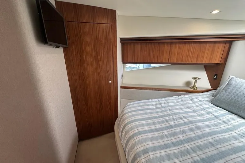 Happy Ours Yacht Photos Pics Interior of 2019 Riviera 5400 Sport Yacht bedroom with wood paneling and striped bedding.