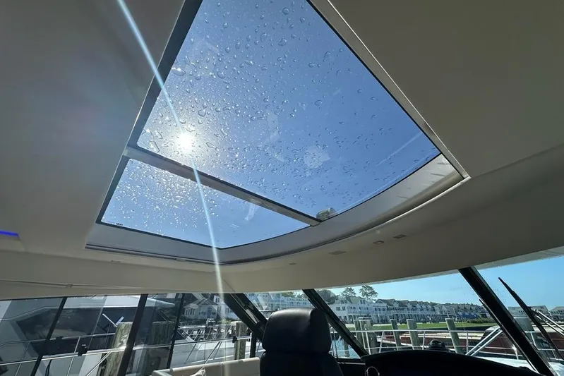 Happy Ours Yacht Photos Pics Sunroof view from 2019 Riviera 5400 Sport Yacht, showcasing clear sky and marina.