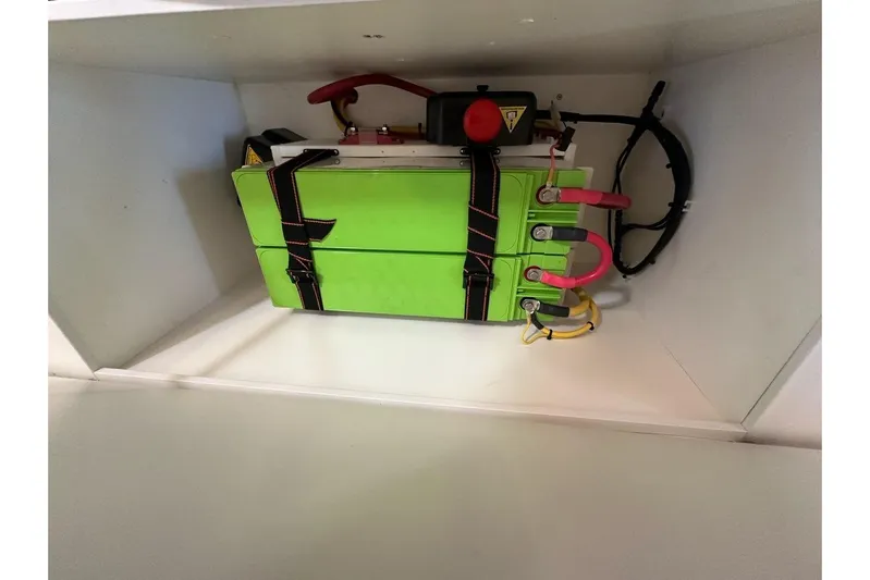 Happy Ours Yacht Photos Pics Green battery compartment in 2019 Riviera 5400 Sport Yacht, featuring secure straps and cables.