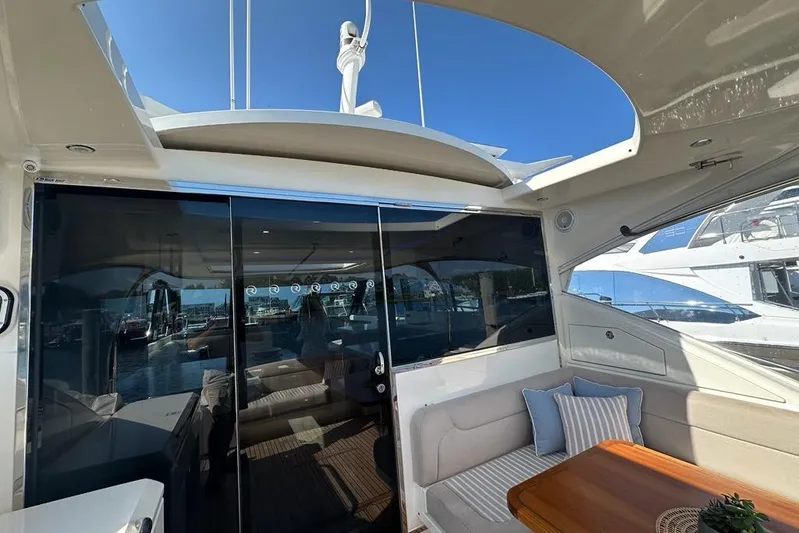 Happy Ours Yacht Photos Pics 2019 Riviera 5400 Sport Yacht interior with seating, table, and glass doors, docked at marina.